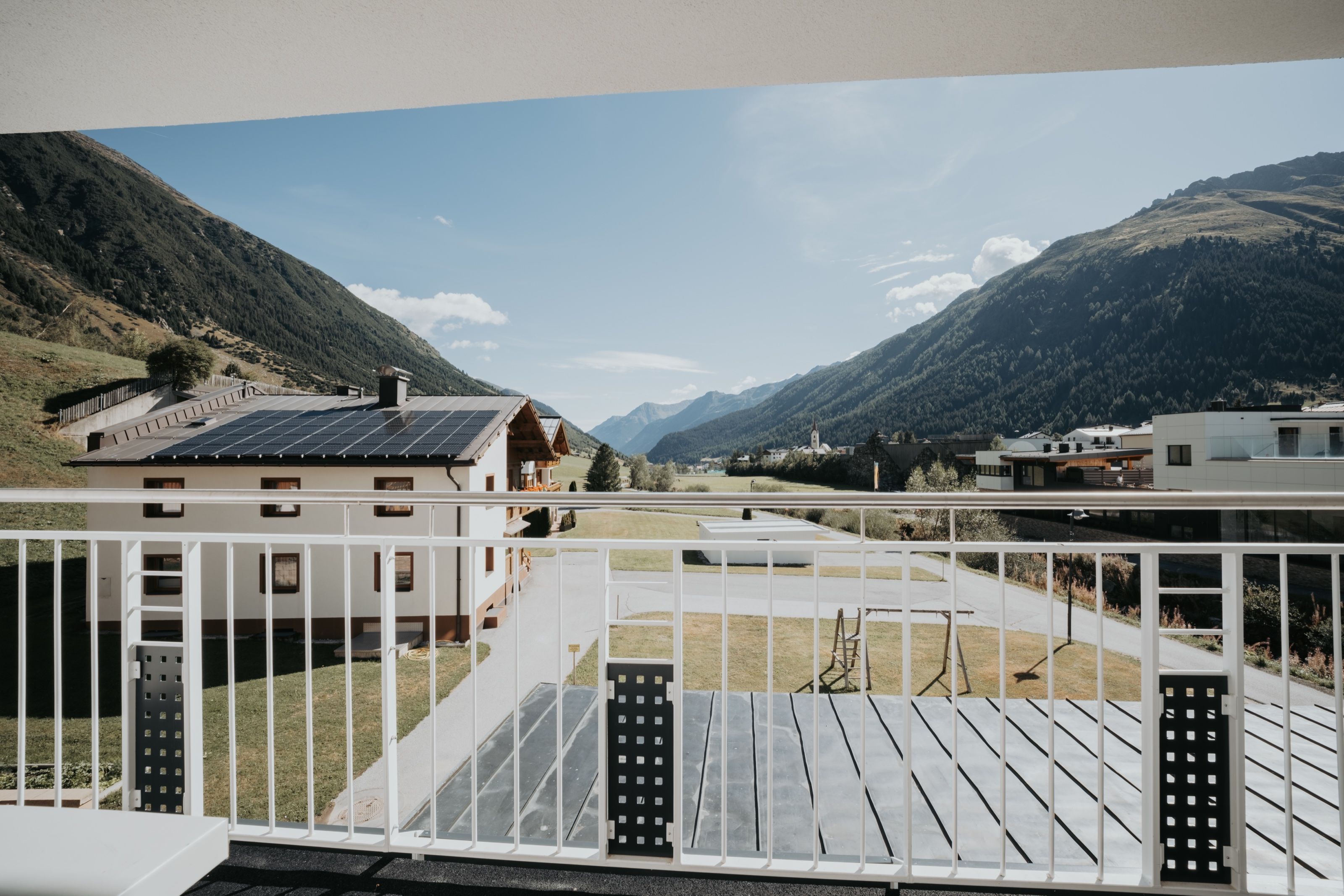 View from a balcony of the house across meadows and neighbouring houses to the church tower of Galtür.