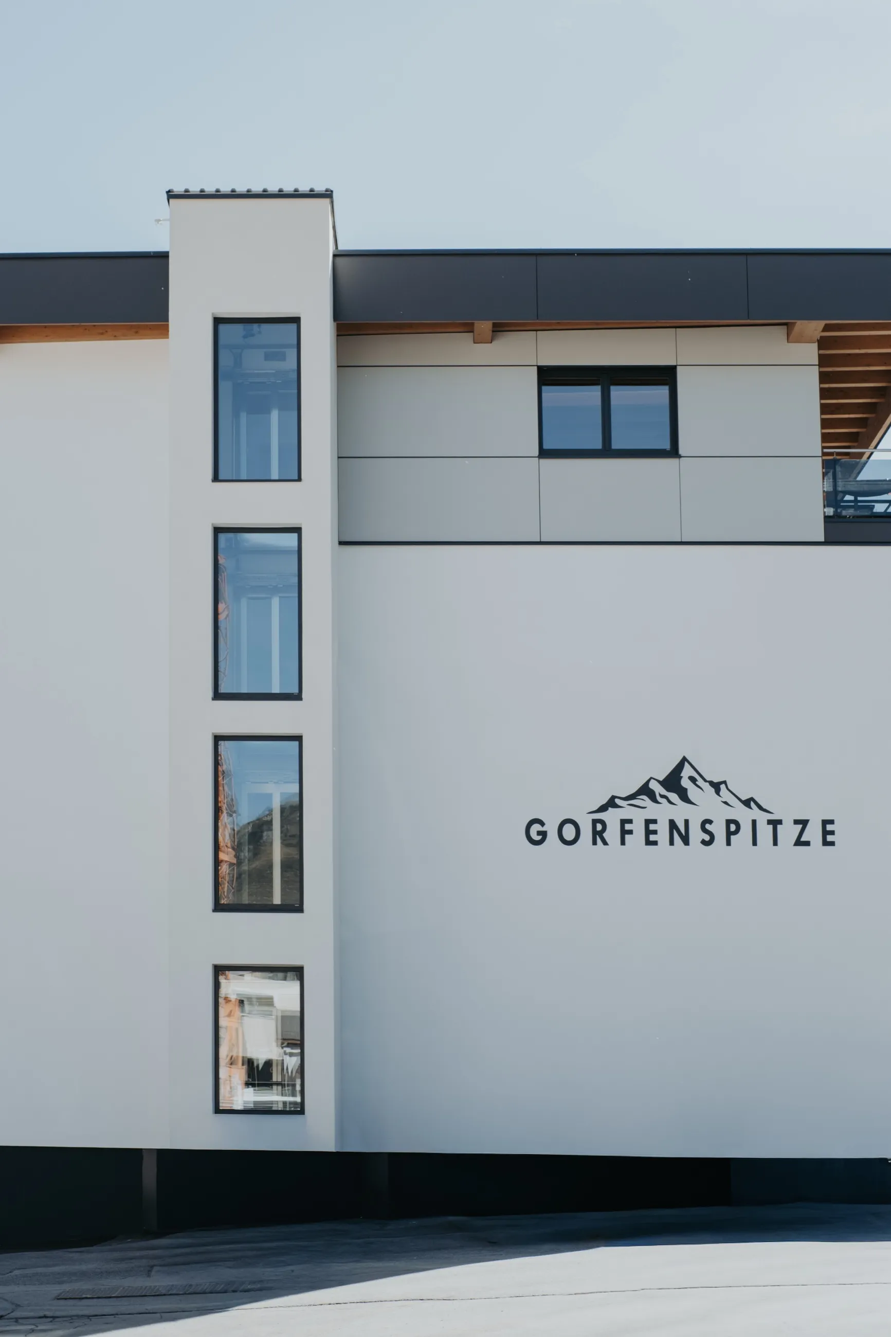 Nahaufnahme der Fassade: das verglaste Fensterband des Panorama-Personenaufzugs, daneben der Schriftzug Gorfenspitze mit Berglogo.