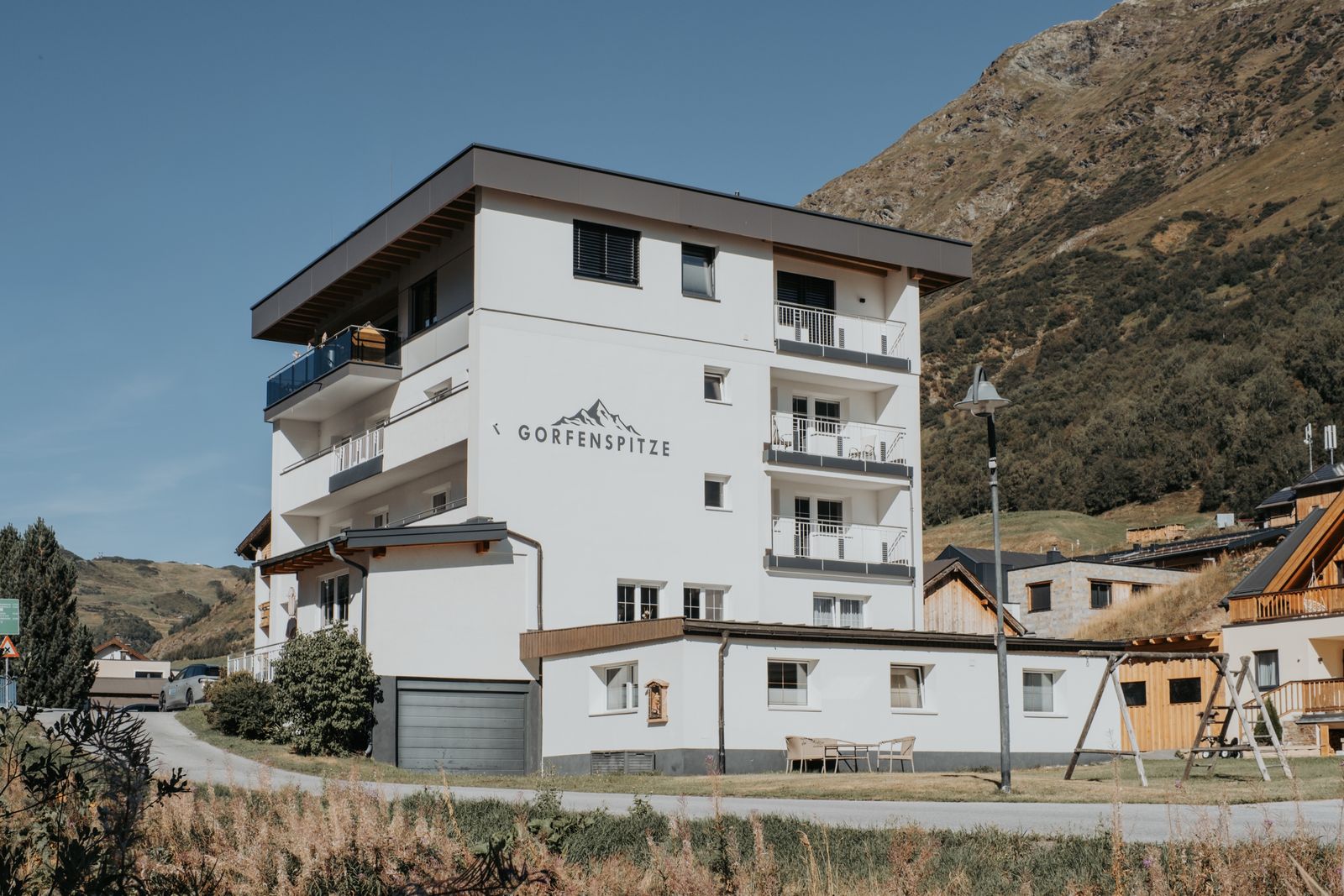 Das Haus Gorfenspitze an einem Spätsommertag, mit dem Schriftzug an der Hausfassade und dem Berghang dahinter.
