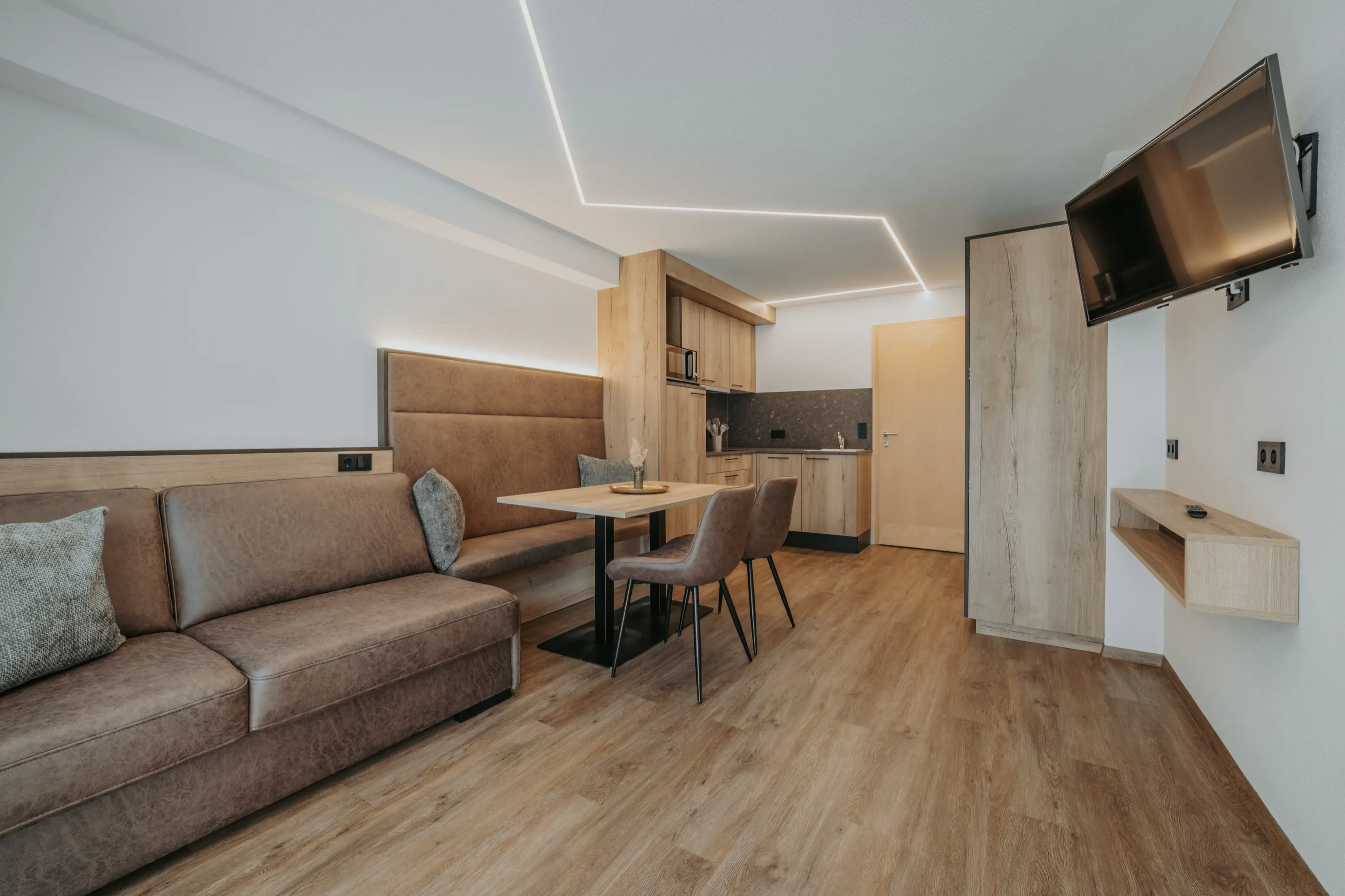 Wohnraum einer Ferienwohnung mit Ledersofa, Essplatz und offener Küchenzeile.